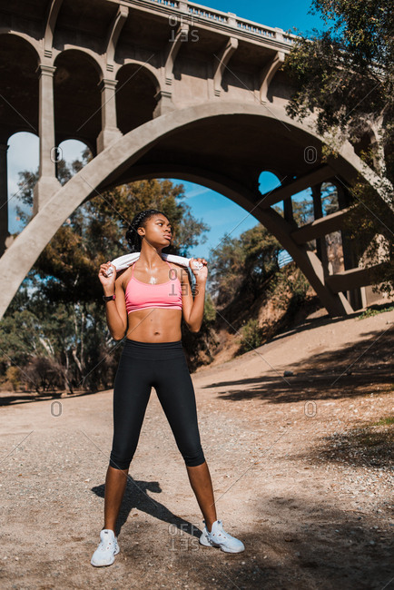 Determined sporty woman with towel looking away against bridge