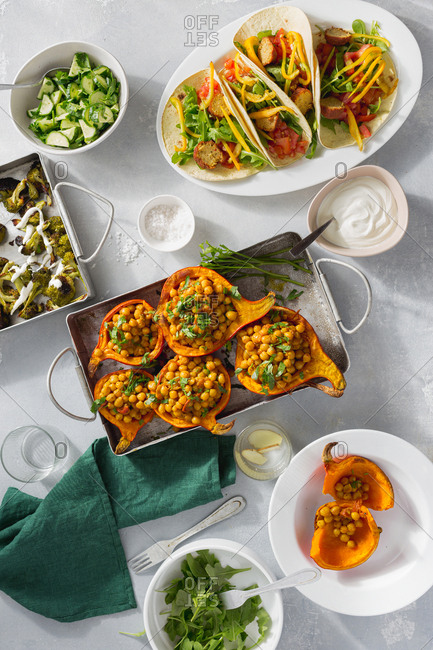 Overhead view dinner table with baked pumpkin with chickpeas curry, tortilla with falafel and salad