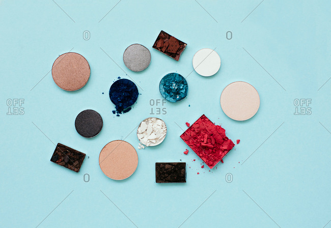 Flatlay of pressed powder makeup on a pale blue background