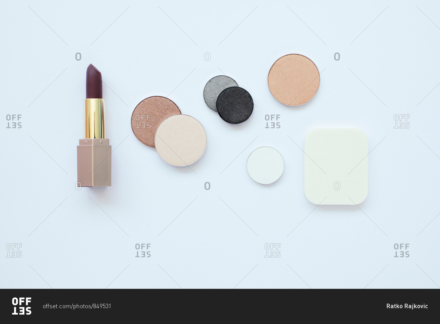 Flatlay of dark lipstick and pressed powders on a white background