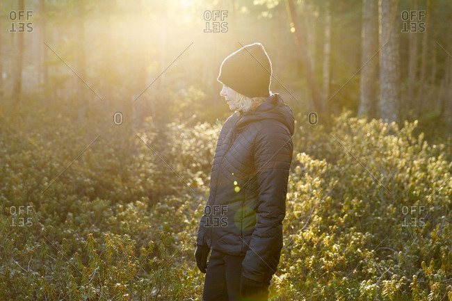 Woman wearing black in sunlit forest
