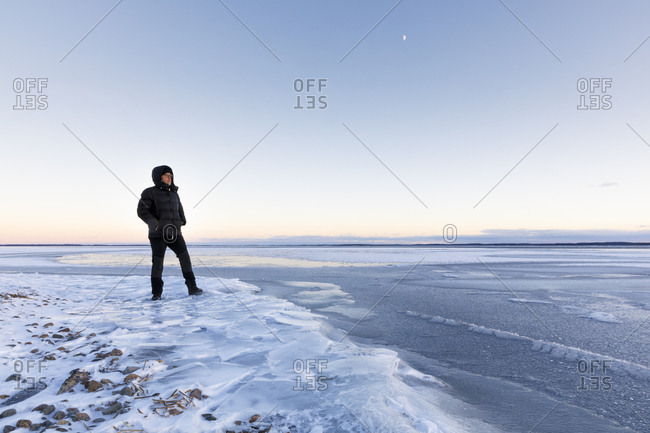 Man standing on frozen Glan lake at sunset in Ostergotland,  Sweden