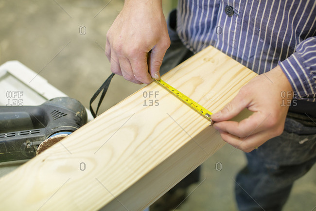 High angle view of carpenter measuring timber