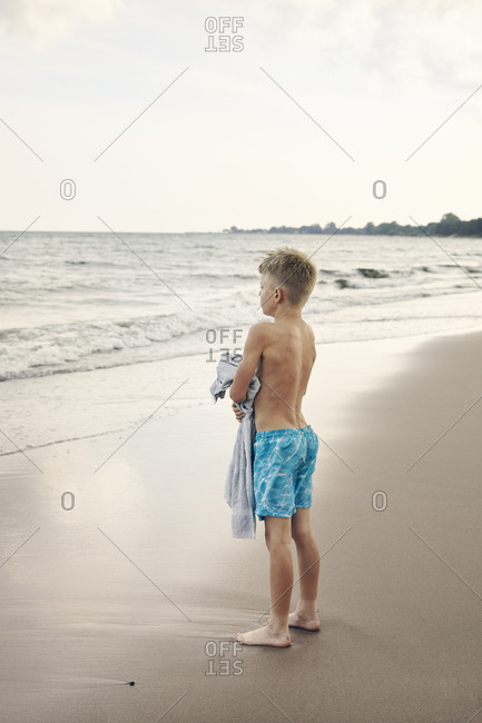 Boy carrying towel on beach