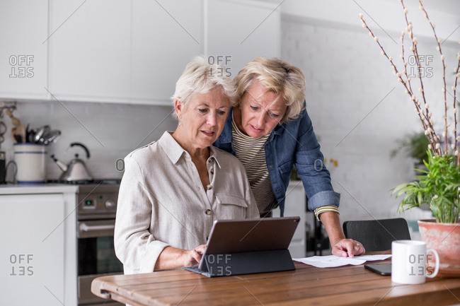 Mature lesbian couple looking at digital tablet together at home