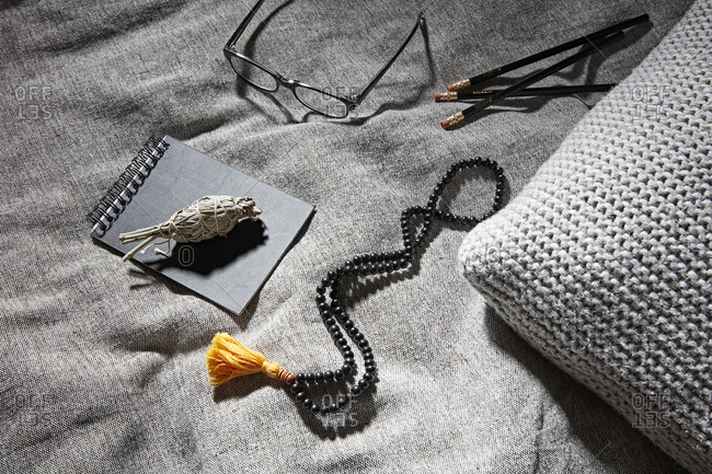 Sage on notebook beside glasses, pencil and prayer beads