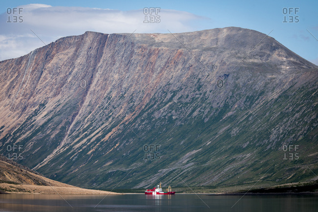 Canada, Newfoundland and Labrador, Torngat Mountains National Park - July 24, 2017: Ship on water with rocky mountain in background Torngats Mountains National Park