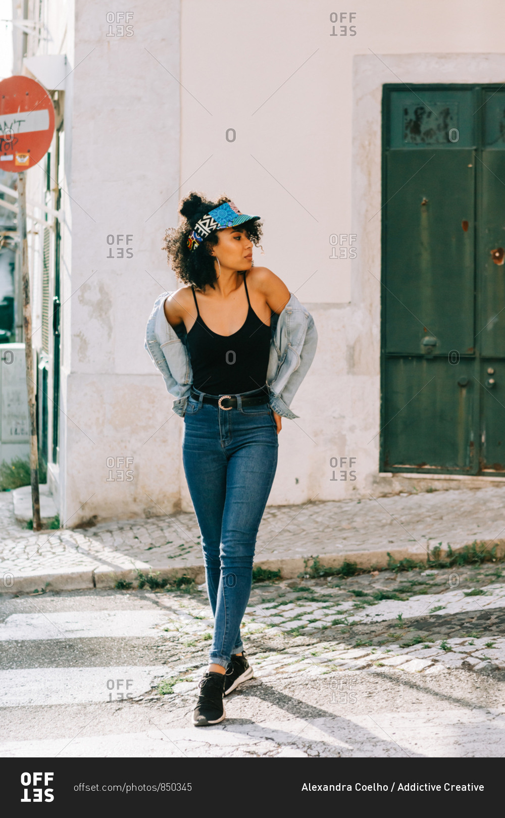 Young cheerful African American woman in jeans and black t-shirt in city street on daytime