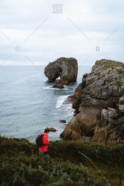Girl in red raincoat exploring the coast of Asturias