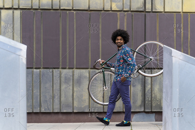 Stylish man carrying bicycle in the city