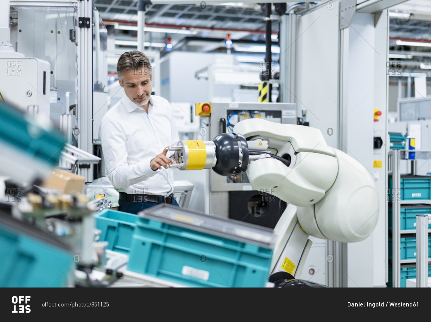 Businessman examining assembly robot in a factory