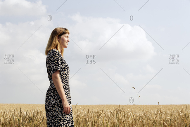 Young woman wearing dress with floral design standing in grain field