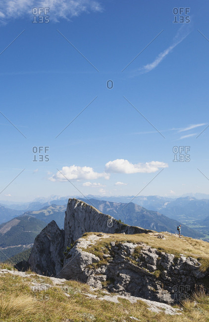 Distant view of hiker standing on Spinnerin peak against blue sky