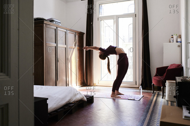 Young brunette woman practicing yoga in student dorm