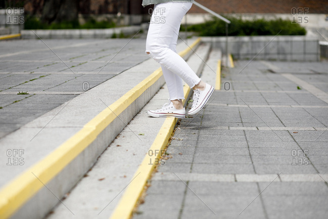 Low section of woman moving up on steps in city