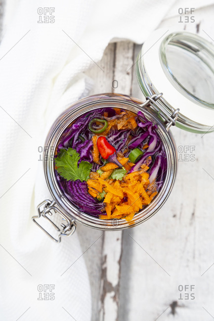 Jar of red cabbage- chili peppers- carrots and coriander on wooden table