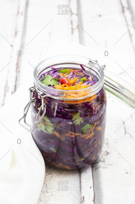 Jar of red cabbage- chili peppers- carrots and coriander on wooden table