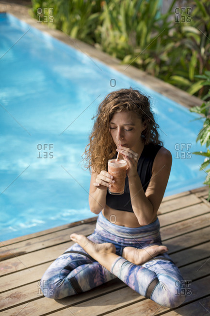 Woman practicing yoga at poolside- drinking juice- Costa Rica