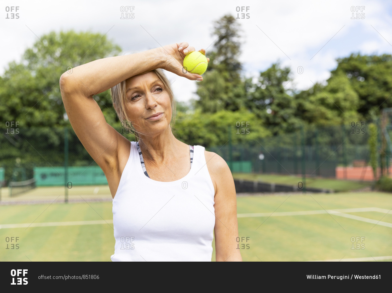 Tired female tennis player taking a break on grass court at tennis club