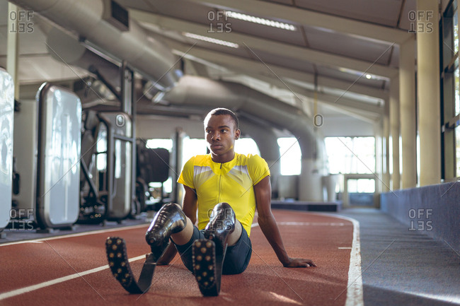 Disabled male athletic relaxing on a running track in fitness center