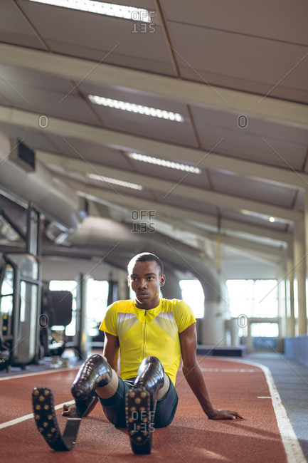 Disabled male athletic relaxing on a running track in fitness center
