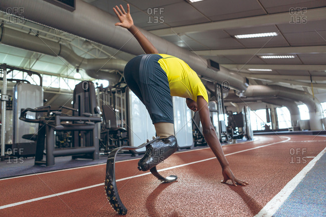 Disabled African American male athletic running on sports track in fitness center