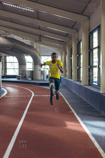 Disabled African American male athletic running on sports track in fitness center