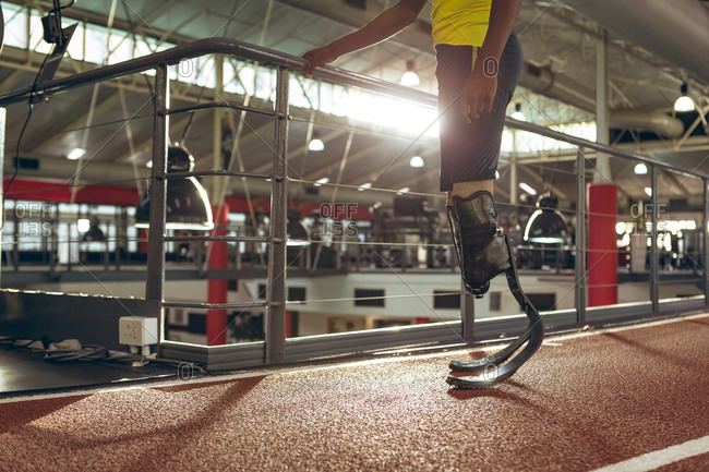 Disabled African American male athletic standing on running track in fitness center