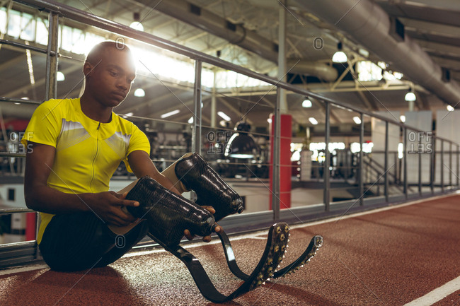 Disabled African American male athletic sitting on race track in fitness center