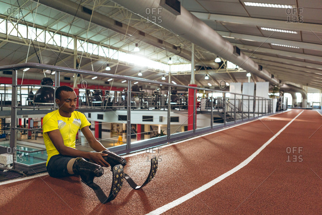 Disabled African American male athletic sitting on race track in fitness center