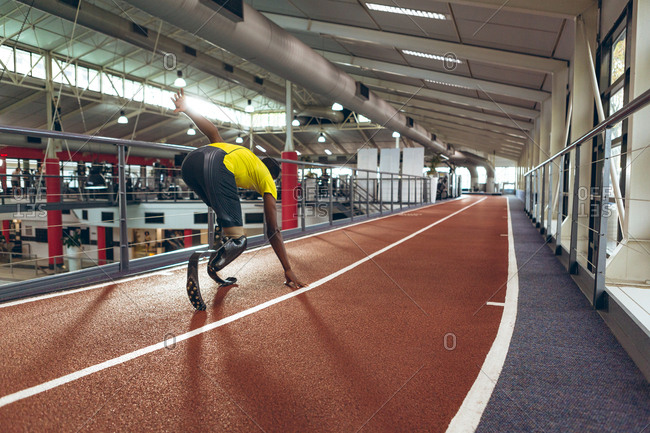 Disabled African American male athletic running on race track in fitness center