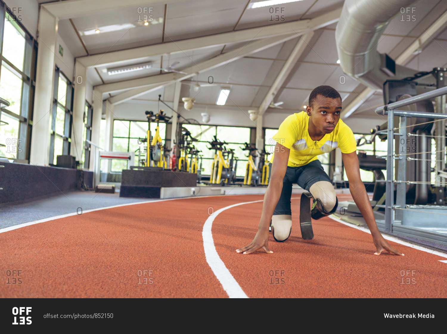 Disabled African American male athletic in starting position on running track in fitness center