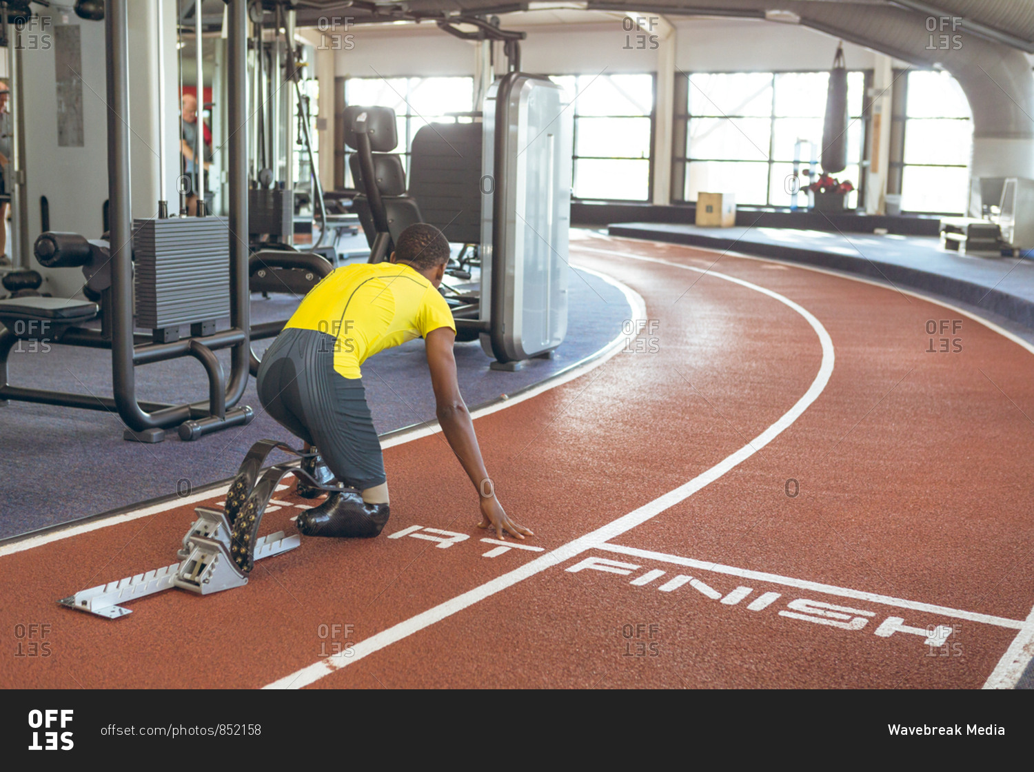Disabled African American male athletic at starting block on running track in fitness center