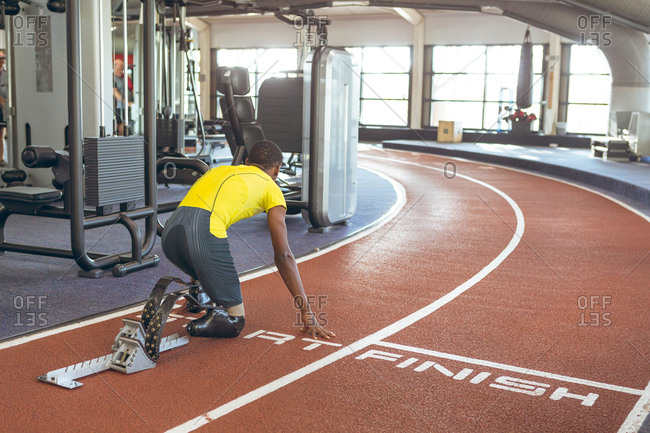 Disabled African American male athletic at starting block on running track in fitness center