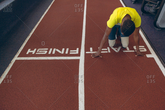 Disabled African American male athletic at starting point on running track in fitness center