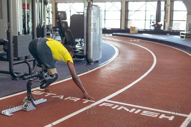Disabled African American male athletic at starting point on running track in fitness center