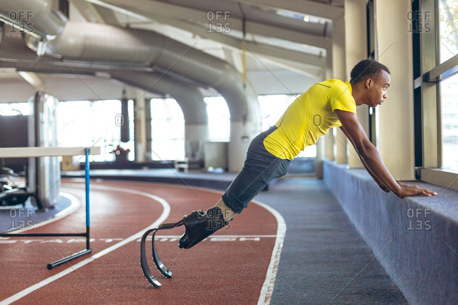Disabled African American male athletic exercising on running track in fitness center