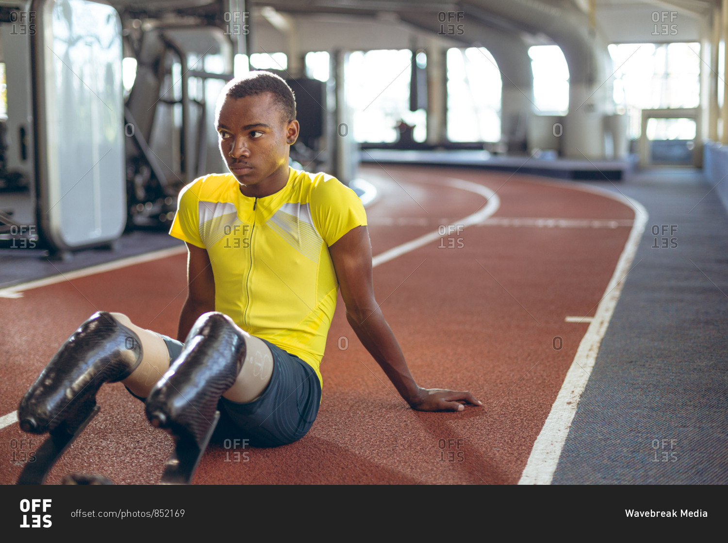 Disabled African American male athletic relaxing on a running track in fitness center