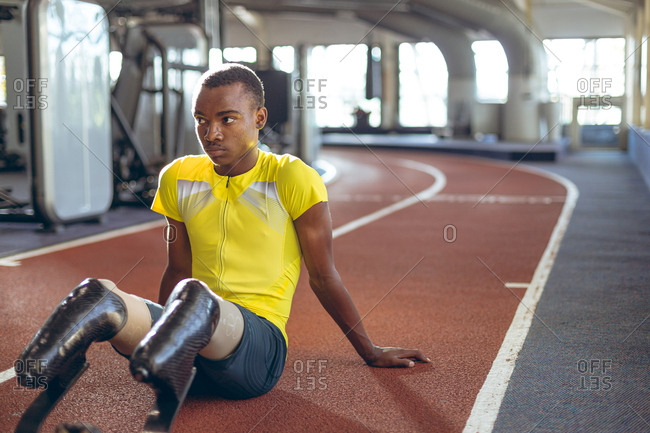 Disabled African American male athletic relaxing on a running track in fitness center