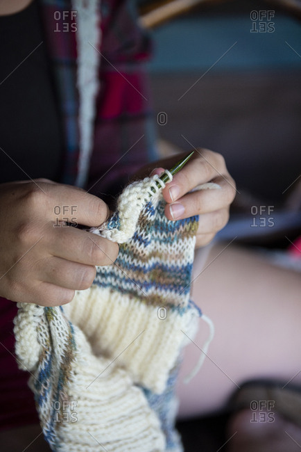 Woman knitting a cream and teal sweater