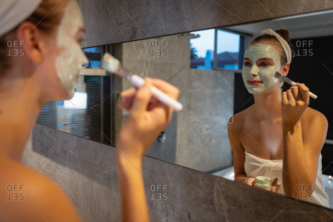 Young woman applying a face mask in a modern bathroom