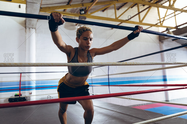 Female boxer exercising in boxing ring at boxing club