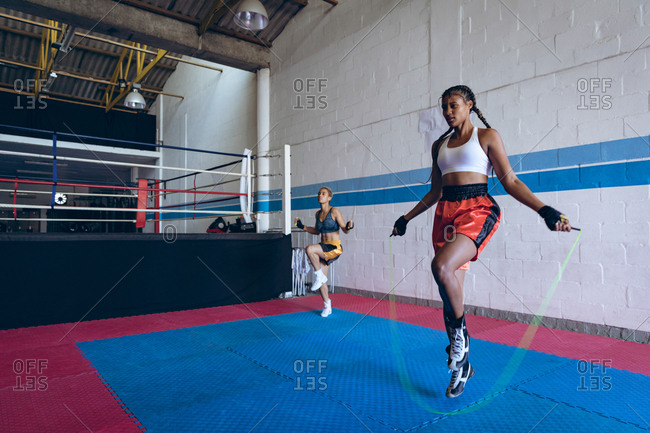 Female boxers exercising with skipping rope in boxing club