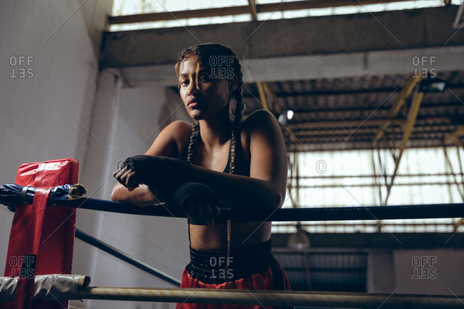 Female boxer leaning on ropes and looking at camera in boxing ring at boxing club
