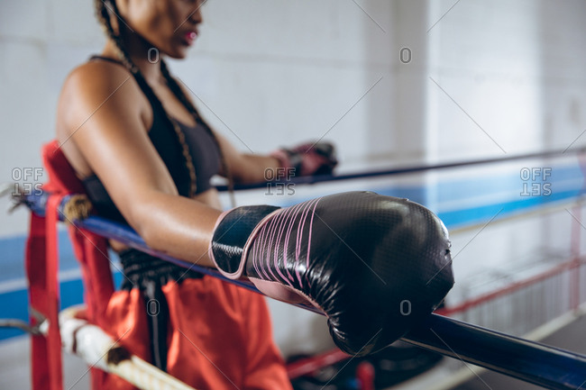 Female boxer resting in the corner of the boxing ring at boxing club