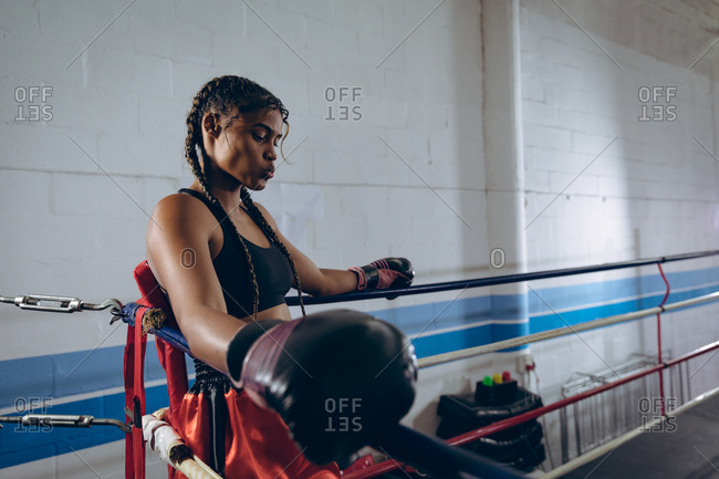 Female boxer resting in the corner of the boxing ring at boxing club