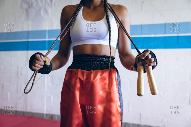 Female boxer standing with skipping rope in boxing club