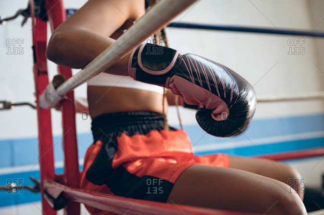 Female boxer relaxing in boxing ring at fitness center
