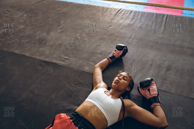 Female boxer lying in boxing ring at fitness center