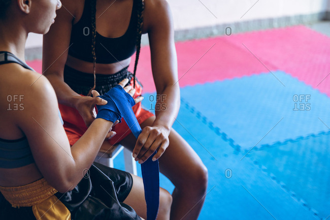 Female trainer putting hand wrap to female boxer in boxing club
